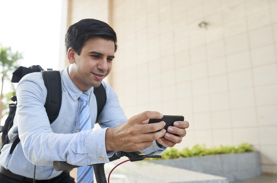 Smiling young handsome entrepreneur playing addictive game on smartphone